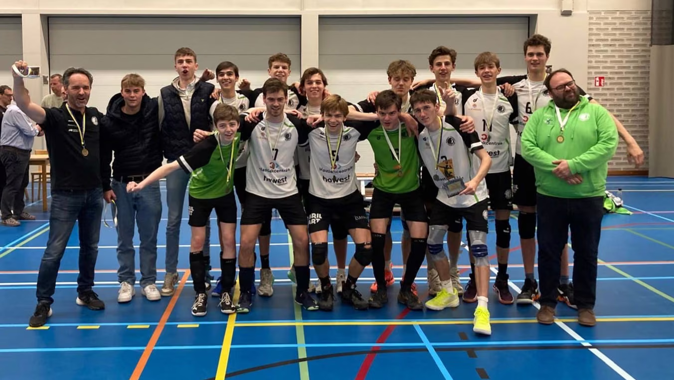 De U19 van Rembert juicht met medailles en coaches in de sporthal na het dubbel kampioenschap tegen Knack Roeselare.