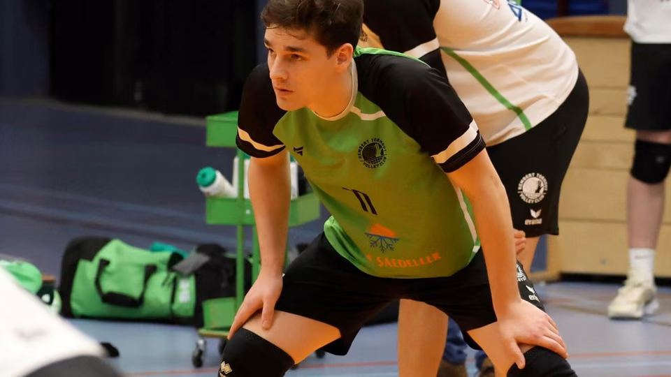 Een Rembert-speler in groen-zwart shirt staat geconcentreerd voorovergebogen, handen op de knieën, klaar voor de derby