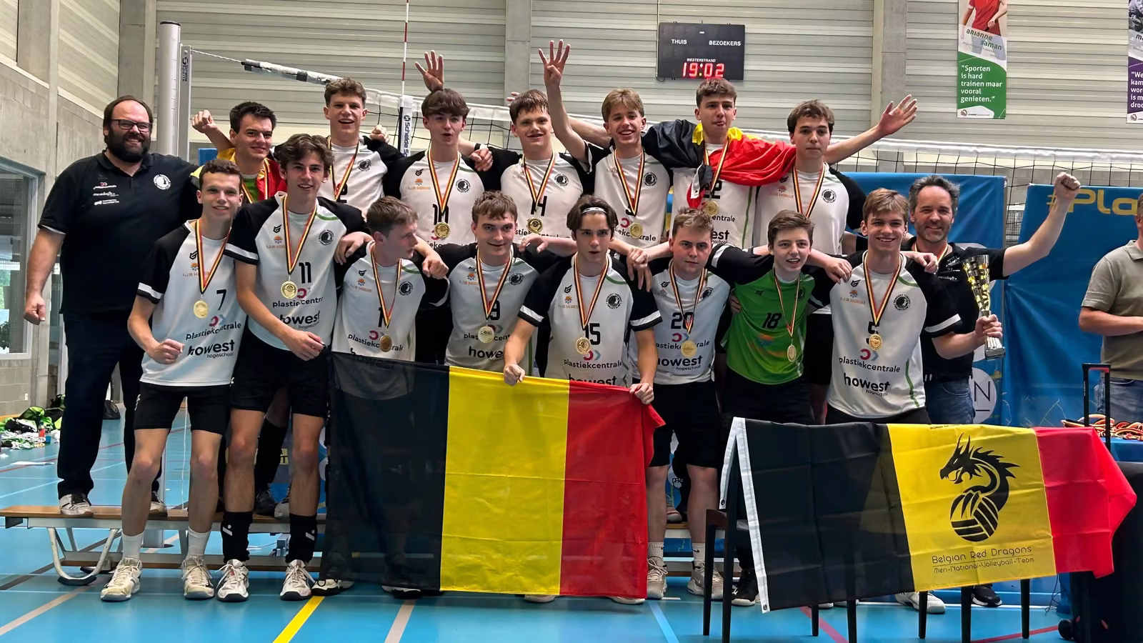 De U19-spelers met gouden medailles en Belgische vlaggen vieren de BK-titel samen met de staf.