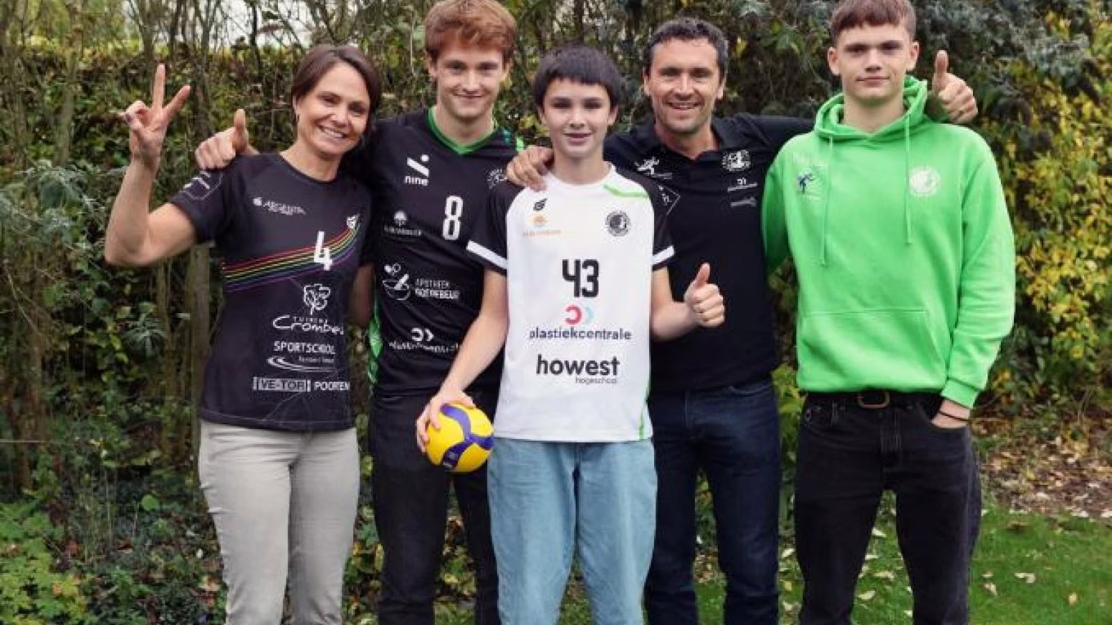 Een gezin van vijf poseert in de tuin in RTH-kledij, een van de zonen houdt een volleybal vast.